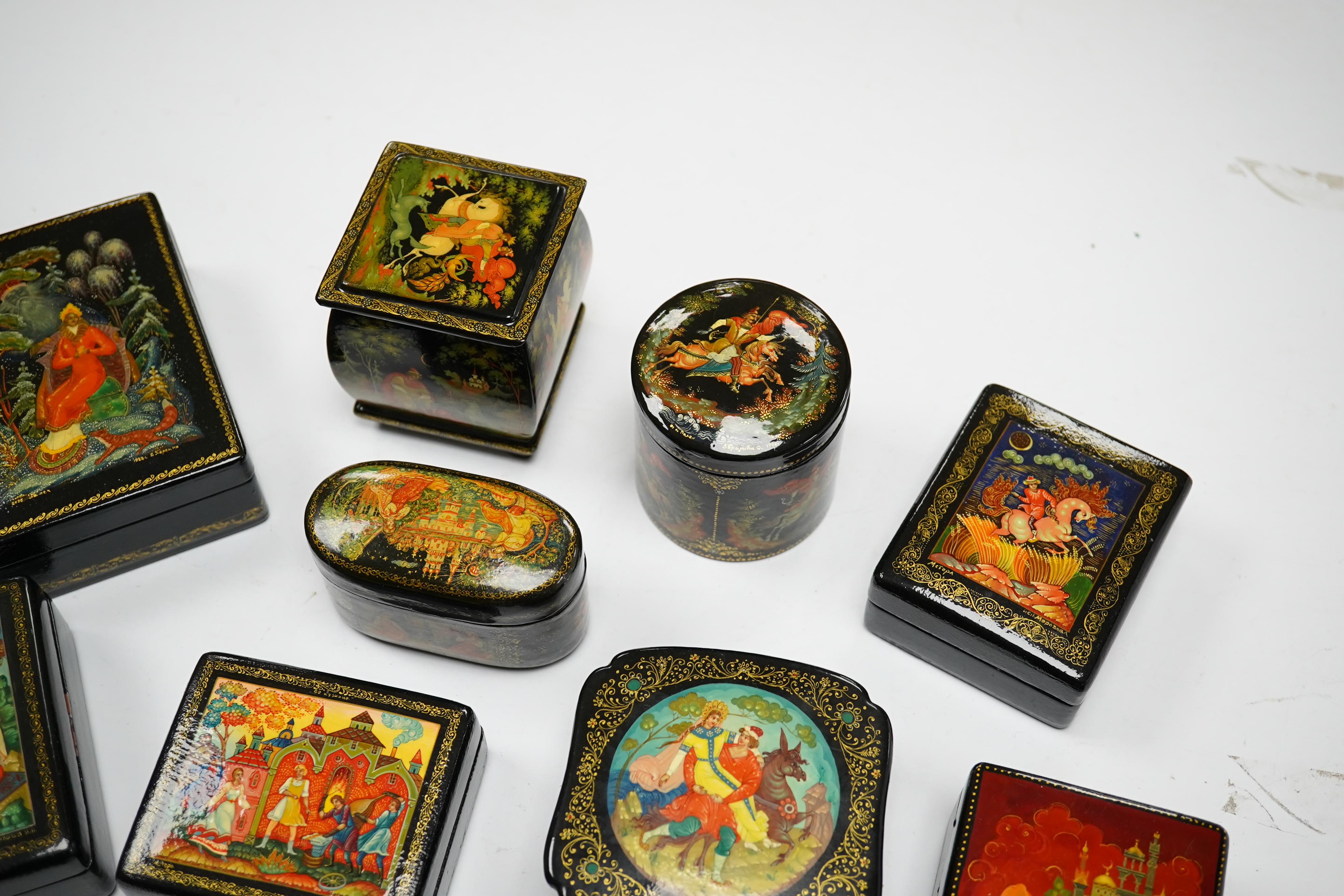 A quantity of Russian lacquer boxes decorated with figures and mythical scenes, largest 10cm in length. Condition - mostly good